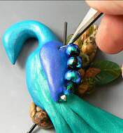 Beads being added to the clay peacock